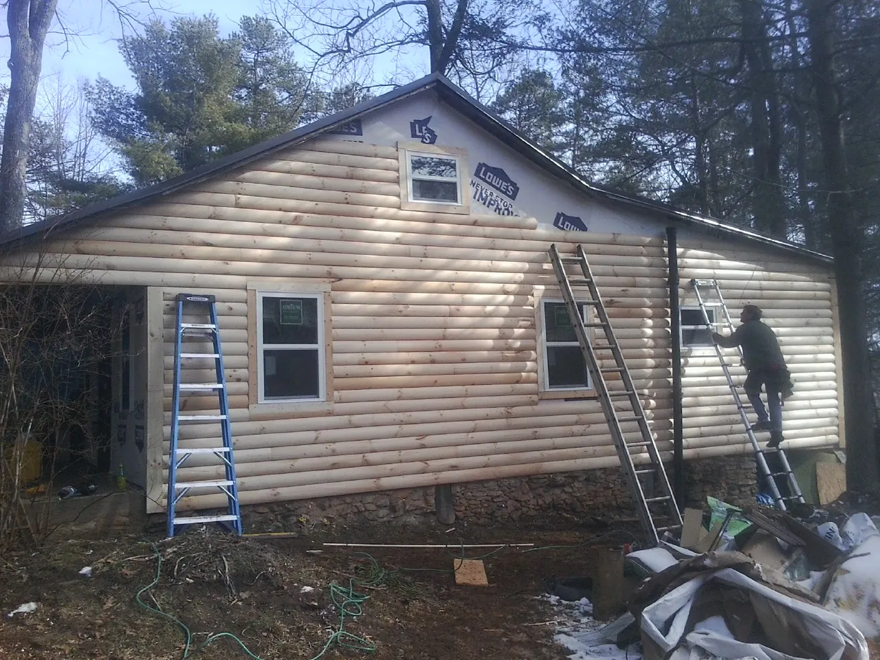 Ladders set against fresh log siding during an exterior remodel in Fayetteville