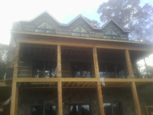 Dormers and porch framing on a large log home under construction — Roof Coating work by our crew in Fayetteville